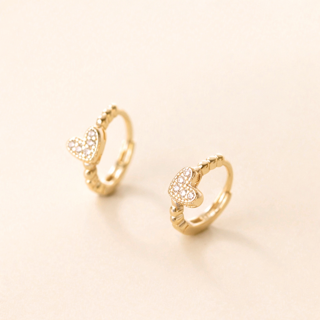 Gold hoop earrings with heart designs on a light beige background